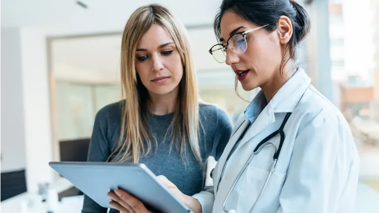 Healthcare professional discussing information on a tablet with a patient during an in-office consultation.