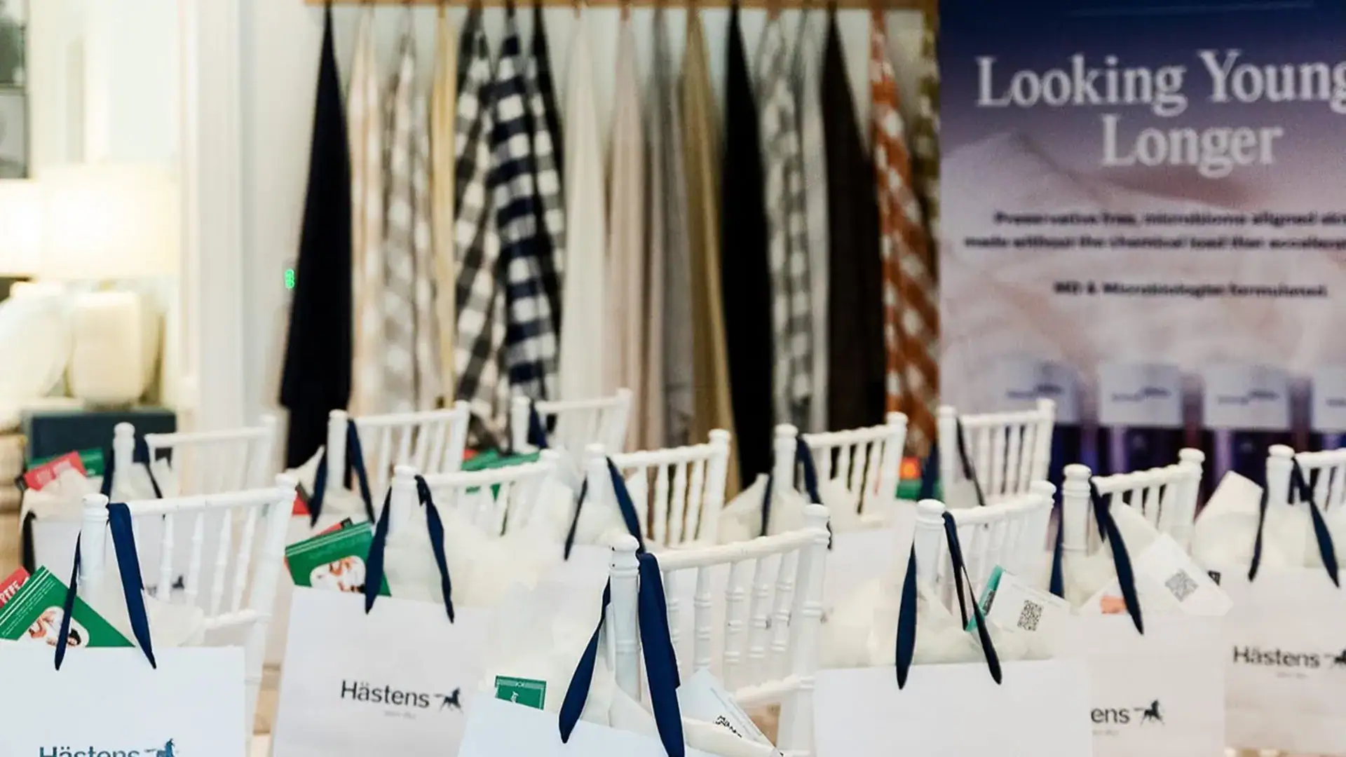 Rows of white gift bags rest on chairs before a women's wellness event, ready for attendees to receive.